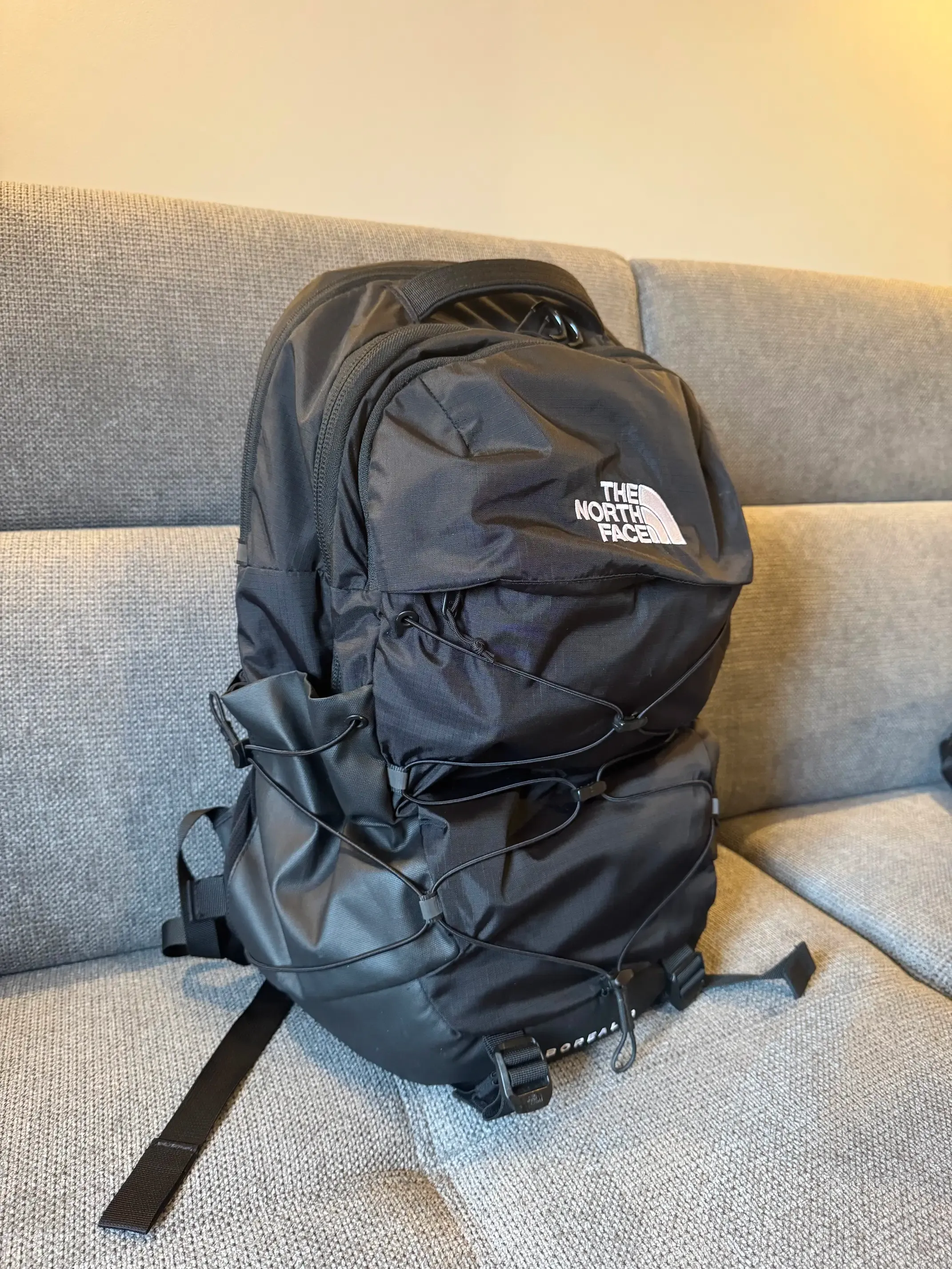 A photo of a black backpack on a gray sofa.