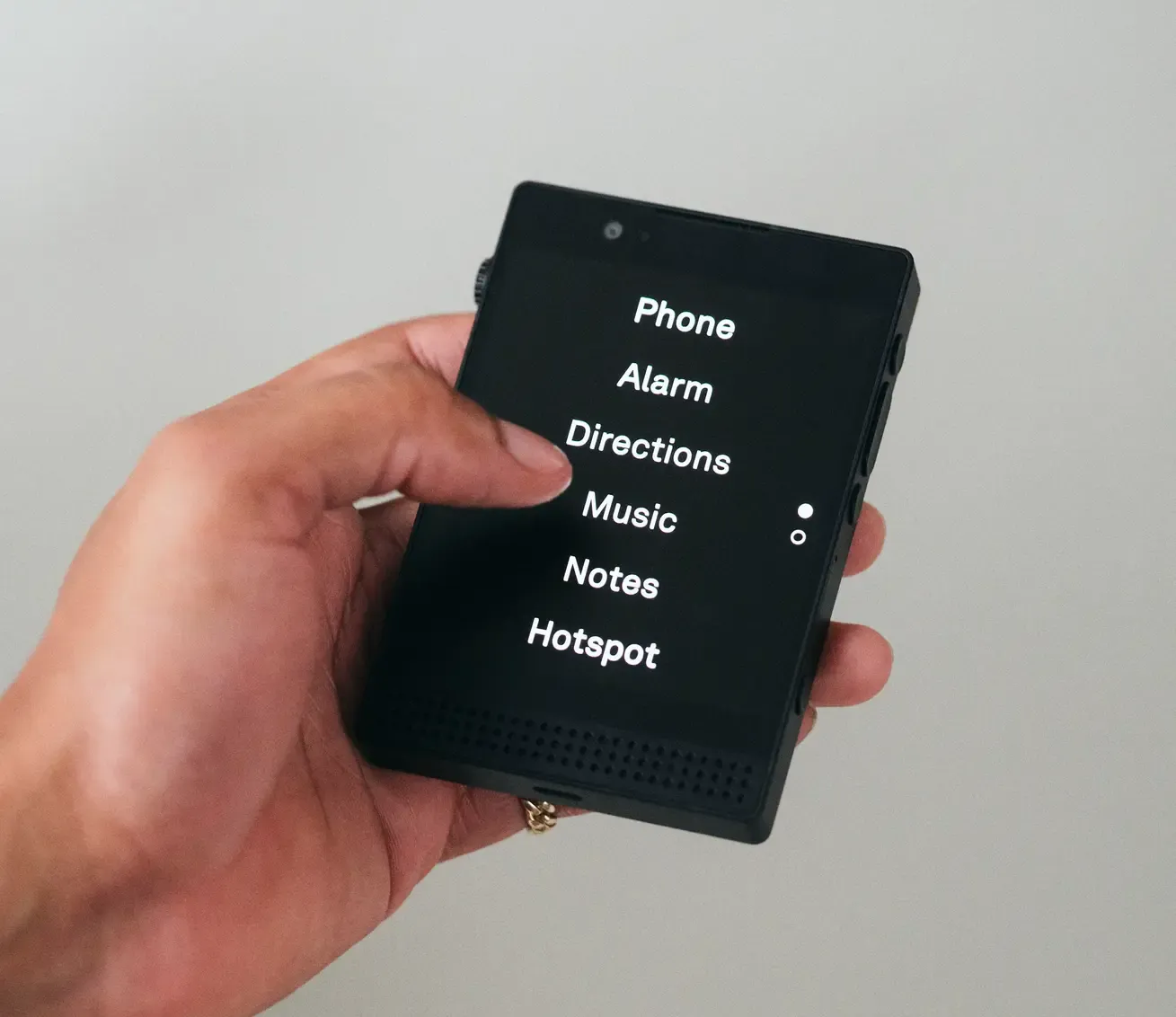 A photo of the Light Phone III. It looks like a black square. The screen is black, with only 6 words displayed on it: Phone, Alarm, Directions, Music, Notes and Hotspot